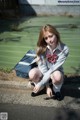 A woman in a school uniform crouching on the ground.