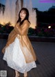 A woman standing in front of a fountain at night.