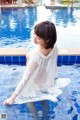 A woman in a white robe sitting in a pool.