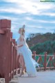 A woman in a white dress standing on a bridge.