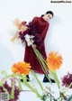 A woman in a red dress holding a bunch of flowers.