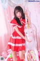 A woman in a red dress standing next to a white horse.