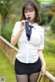 A woman in a white shirt and black skirt holding a black tie.