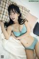 A woman laying on a bed in a blue bra and panties.