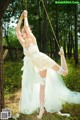 A woman in a white dress is tied up to a tree.