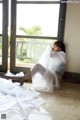 A woman sitting on the floor in front of a window.