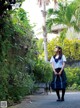 A woman in a school uniform holding a blue bag.