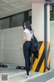 A woman in a white shirt and black leggings is walking down the street.