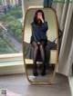 A woman sitting on a bench in front of a mirror.