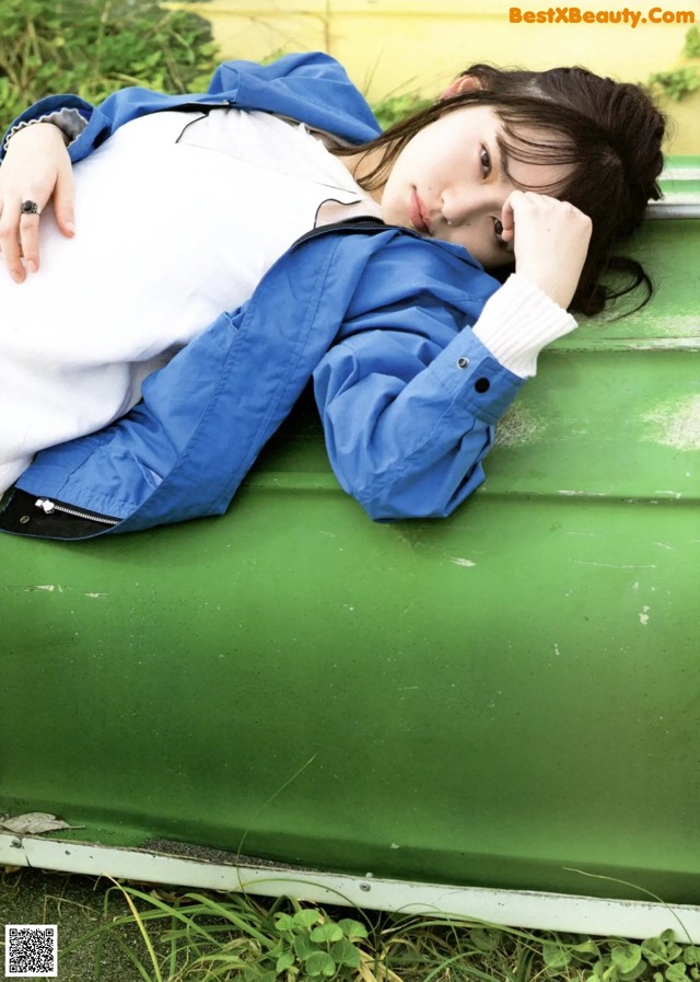 A woman laying on top of a green car.