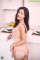 A woman in a pink lingerie posing in a kitchen.