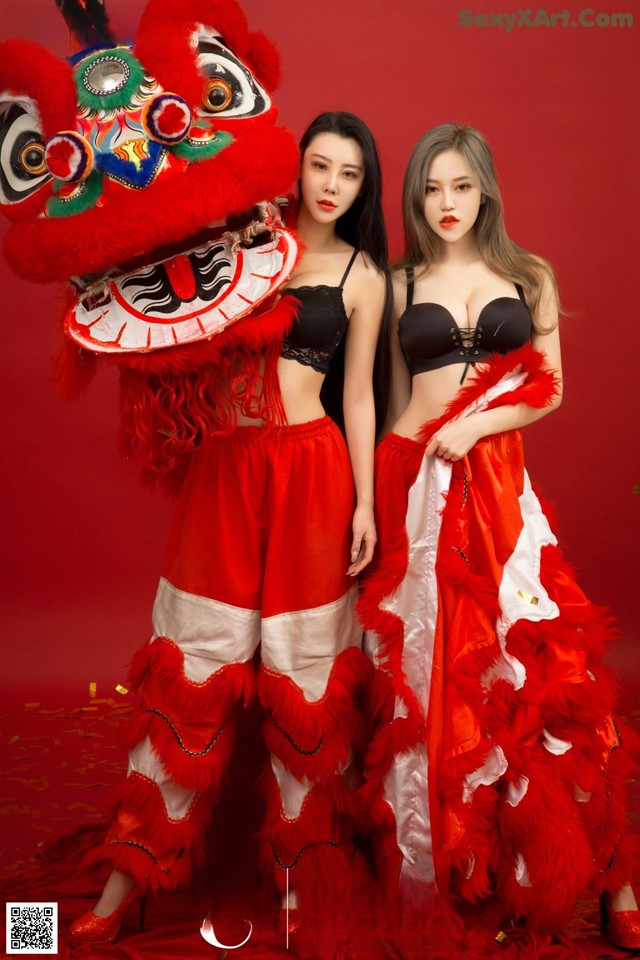 A couple of women standing next to each other in front of a lion.