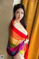 A woman in a colorful shawl leaning against a wall.