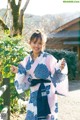 A woman in a blue and white kimono standing in front of a house.