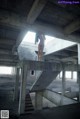 A naked woman standing on a set of stairs in an abandoned building.