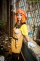 A woman in a yellow coverall and a hard hat posing for a picture.