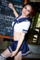 A woman in a school uniform posing in front of a blackboard.