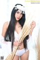 A woman in a white lingerie holding a bunch of wheat.