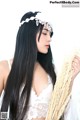 A woman with long black hair holding a bunch of wheat.