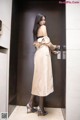 A woman in a trench coat standing in an elevator.