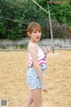 A woman in a pink and white striped top and denim shorts.