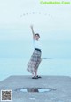 A woman standing on a pier with her arms outstretched.