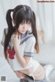 A woman in a school uniform posing on a bed.