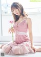 A woman in a pink dress holding a pink flower.