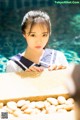 A woman in a sailor outfit leaning on a ledge by a pool.