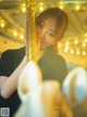 A woman is posing on a carousel with a unicorn.