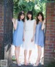 A group of three women standing next to a brick wall.