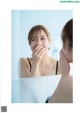 A woman looking at her face in the mirror.